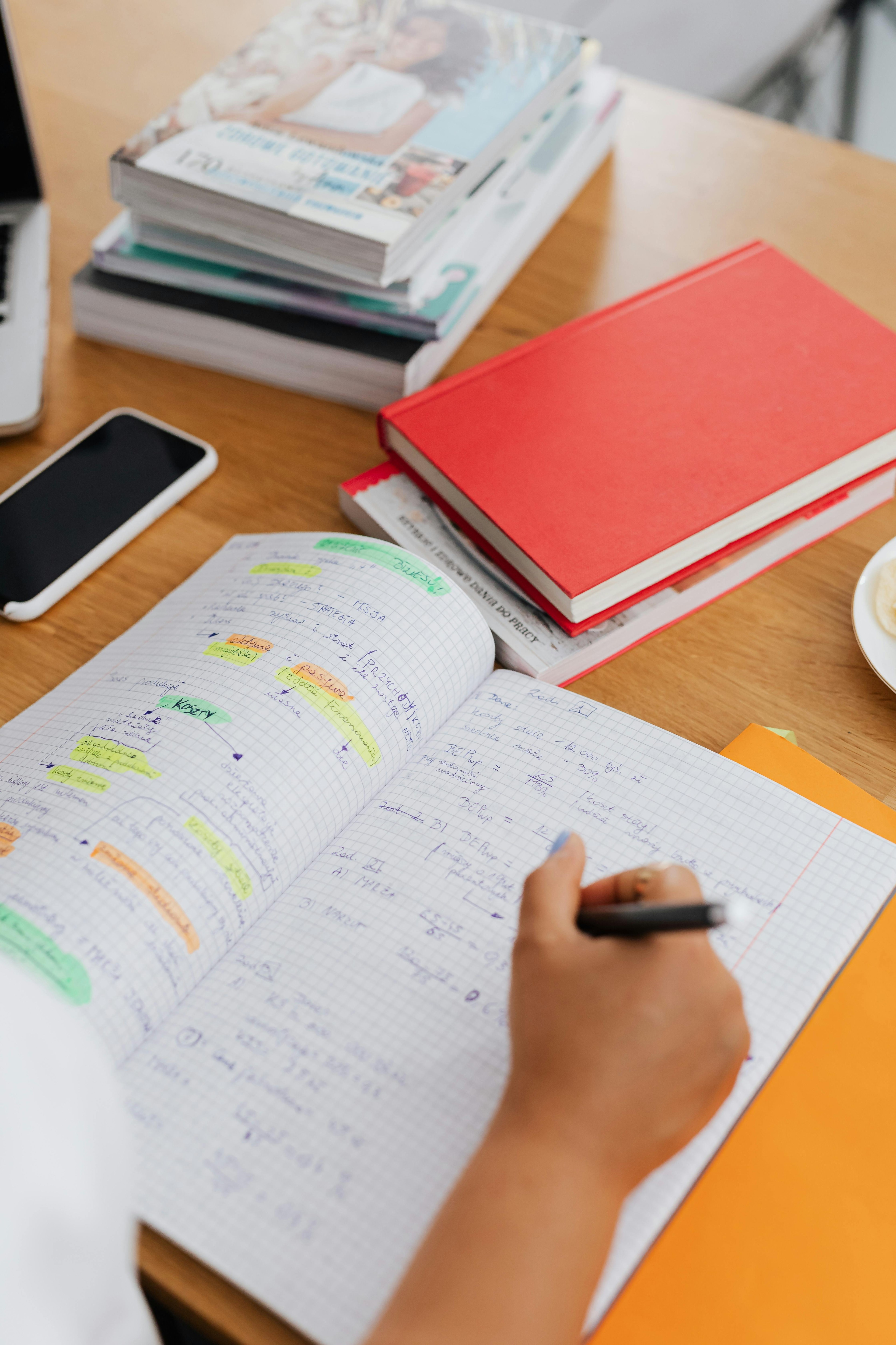 Student taking organised notes while studying with course materials